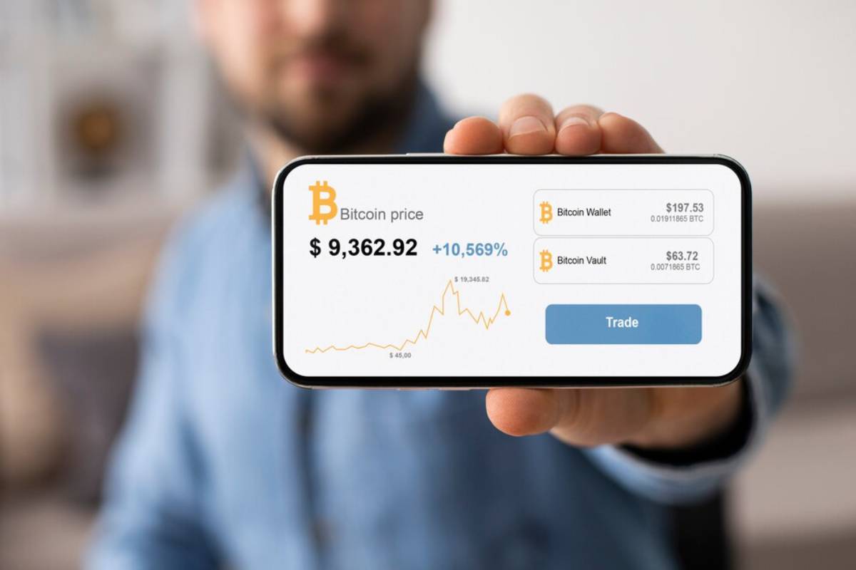 A man displays a smartphone screen showing Bitcoin price and wallet details.