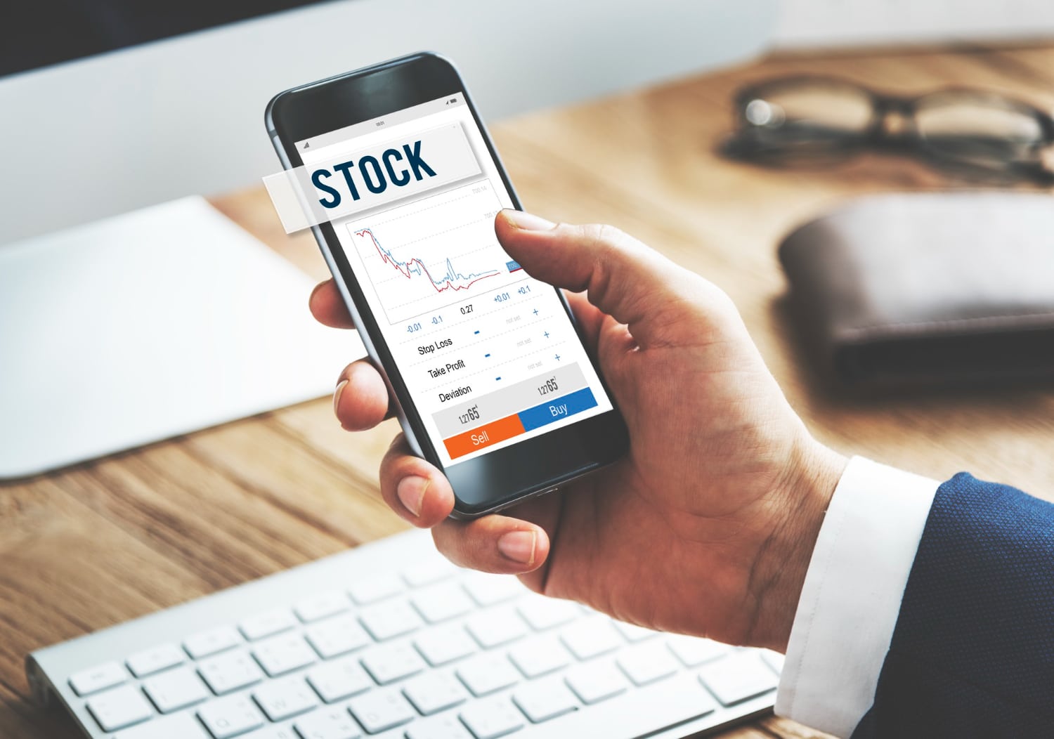 A person checks stock market data on a smartphone in an office setting.